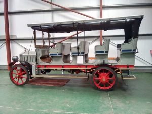 An old fashioned grey bus with red wheels