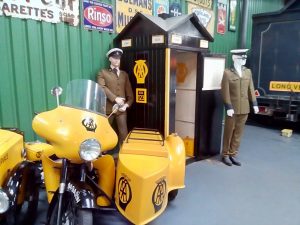 A yellow motorbike and sidecar branded with the old AA logo
