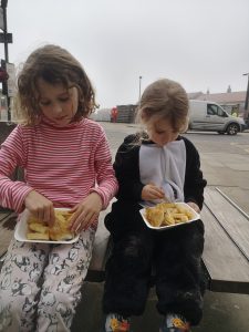 2 girls eat fish and chips from cartons