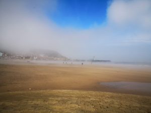 the beach is covered in mist but the sky is blue