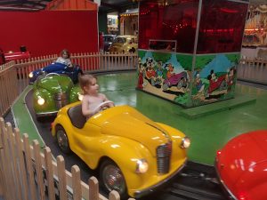 there are 4 little cars in primary colours. 2 girls ride in them happily