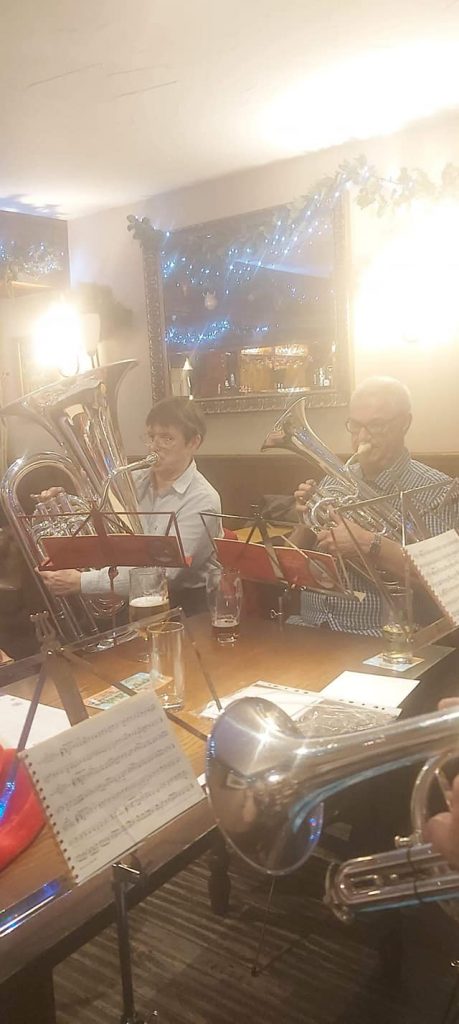 Band members play carols in a pub, wearing festive clothes
